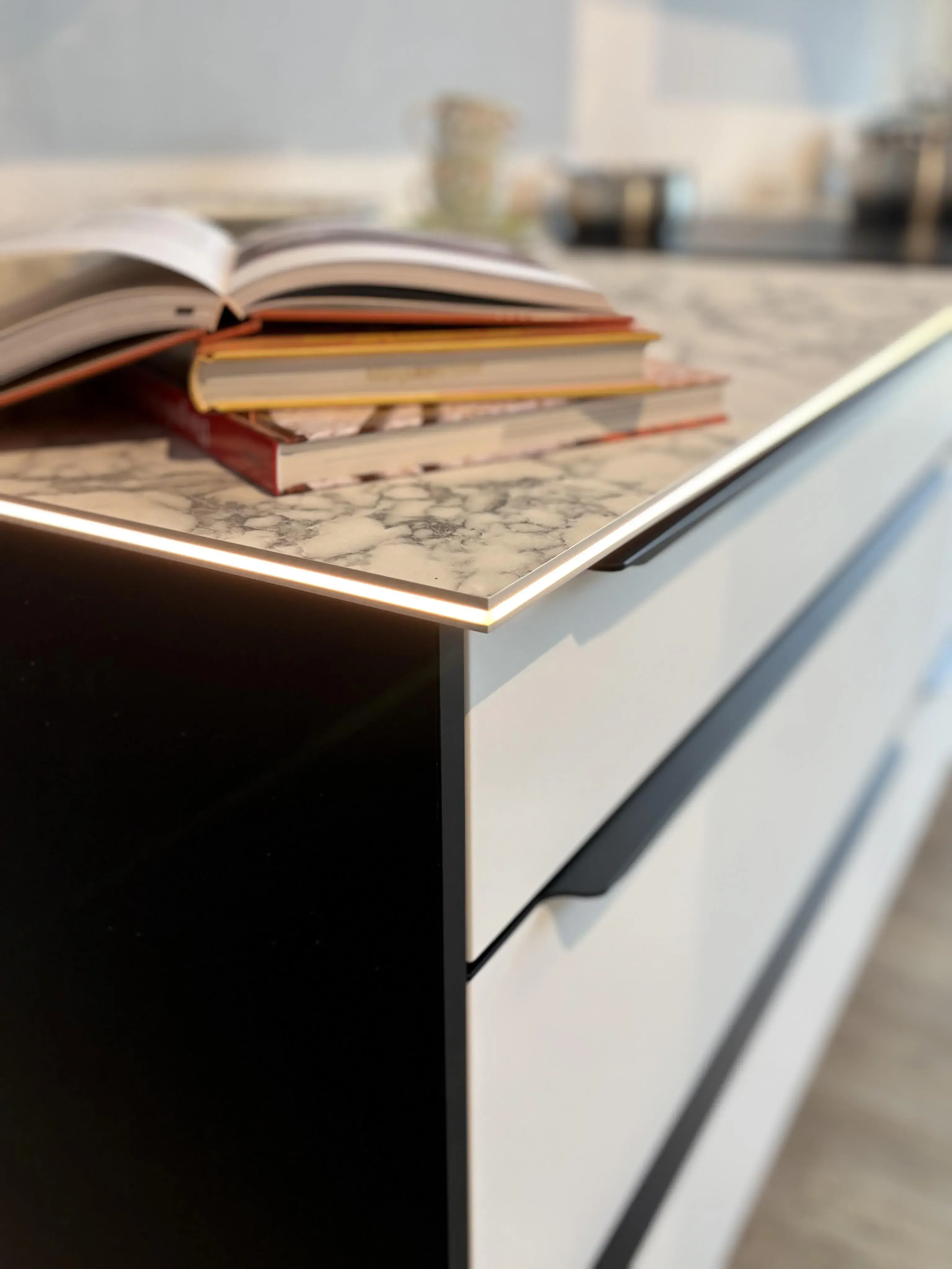 Aufgeschlagene Bücher liegen auf einer modernen Küchenarbeitsplatte.